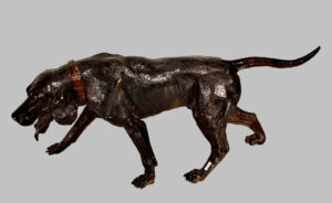 Perro de bronce pavonado con correa y mirando al suelo