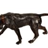 Perro de bronce pavonado con correa y mirando al suelo