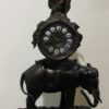 Reloj de sobremesa de bronce pavonado: Elefante sobre base de bronce, reloj circular y ángel en parte superior. S. XIX